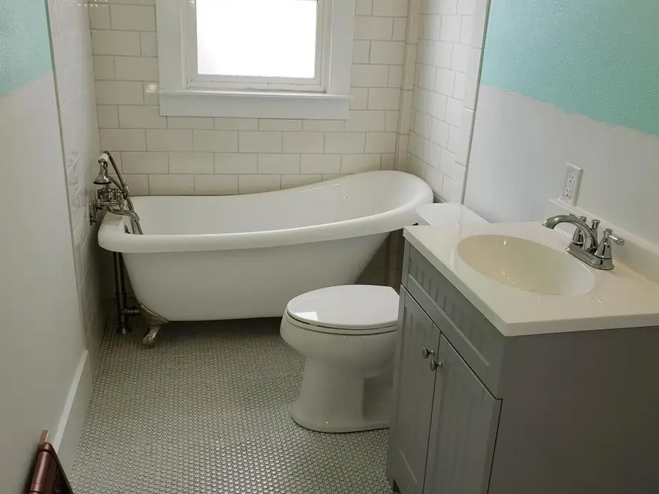 Clawfoot slipper tub in a bathroom with subway tile and a hex tile floor
