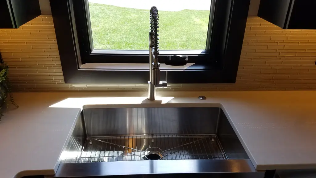 Stainless farmhouse kitchen sink with a pull-down faucet under a window