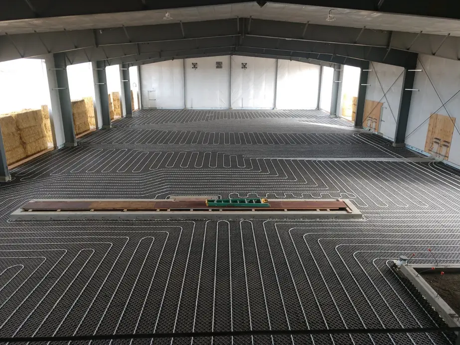 Radiant PEX heating loops laid across a warehouse floor before the concrete pour