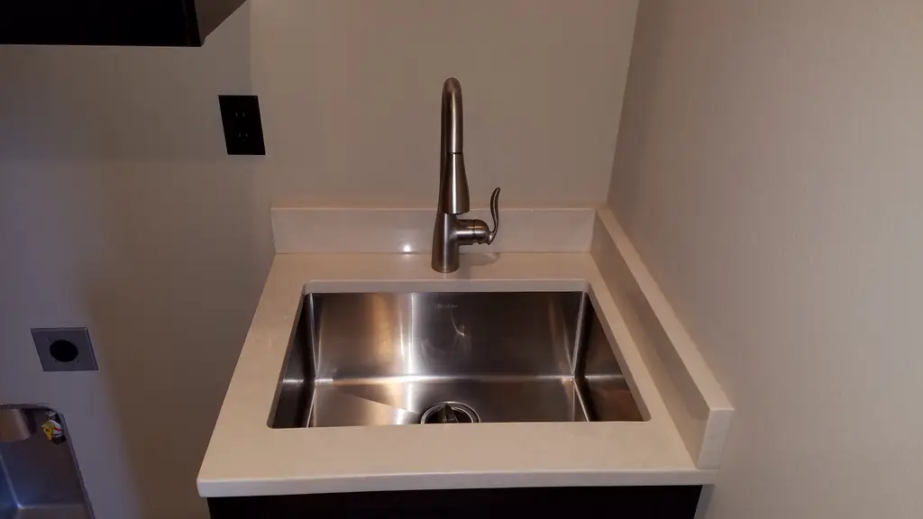 Square stainless utility sink set into a quartz counter with a brushed nickel faucet